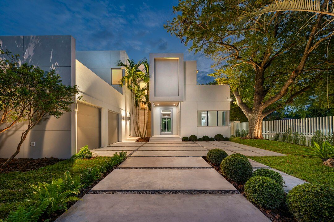 Grand villa exterior illuminated at dusk with a manicured driveway